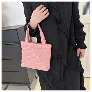 Detail of pink quilted tote bag with heart patterns and gold snap button closure