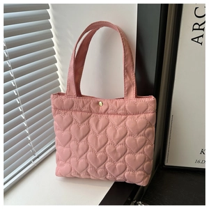 Detail of pink quilted tote bag showing heart patterns and a gold metal buckle closure