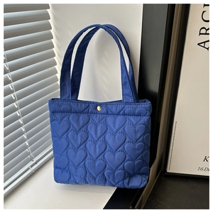Close-up of heart-patterned quilted tote bag with a golden snap closure and sturdy handles