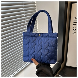 Detail showing Klein blue heart quilted fabric texture and a gold magnetic snap closure