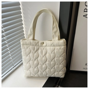 Close-up of heart-quilted puffer tote bag with premium golden snap button closure