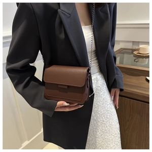 Side view of dark brown PU leather chain bag worn with a professional blazer