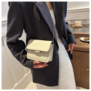 Chic cream leather crossbody bag with silver chain strap shown in a lifestyle setting