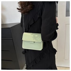 Close-up of mint green PU leather crossbody bag with silver chain strap on model