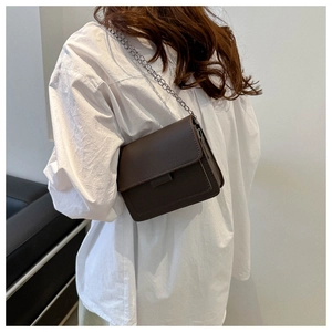 Detail of minimalist dark brown PU leather crossbody bag with slim metal chain strap