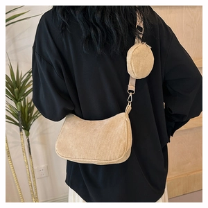 Detail of beige corduroy crescent bag with adjustable wide strap and coin purse charm