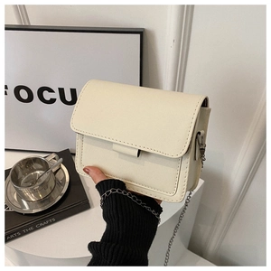 Detail of cream white PU leather crossbody bag with silver chain strap and neat stitching