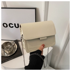 Detail of minimalist beige square crossbody bag with elegant silver metal chain strap