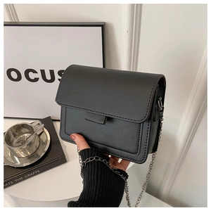 Detail of minimalist black leather crossbody bag with chain strap and fine stitching