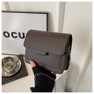 Close-up of a dark brown crossbody bag with refined stitching and silver chain strap details