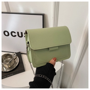 Detail of light green faux leather crossbody bag with silver chain strap and top stitching