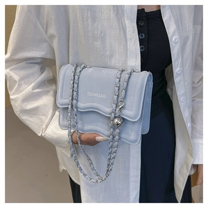 Détail du sac à rabat bleu clair avec bandoulière chaîne argentée et bijou de sac
