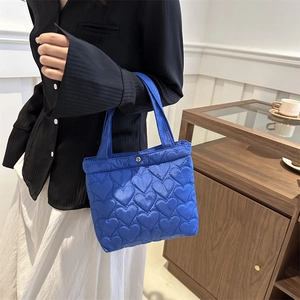 Royal blue quilted tote bag with heart patterns shown in a stylish lifestyle setting