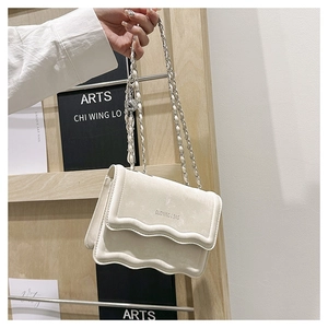 Détail du sac à main blanc en daim avec bord ondulé et bandoulière en chaîne de métal