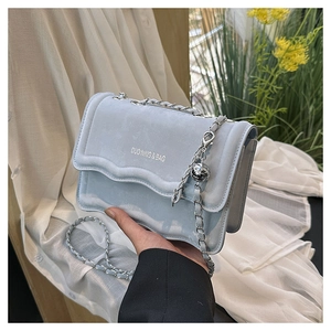 Détail du sac bandoulière en daim bleu clair avec rabat ondulé et chaîne argentée