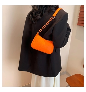 Close-up of orange crocodile pattern baguette bag with stylish matching chain strap detail
