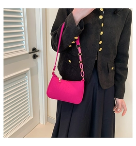 Detail of light pink crocodile pattern underarm bag with gold zipper and stylish chain