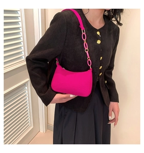 Close-up of a vibrant pink chain baguette shoulder bag with textured finish and strap