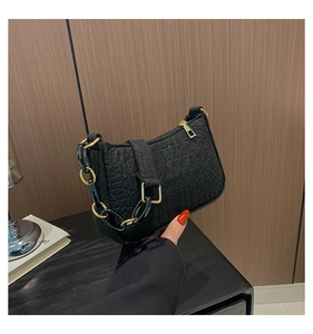 Close-up of black crocodile pattern leather bag with golden and black chain strap