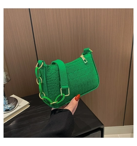 Detail of green crocodile texture handbag with thick resin chain and gold hardware