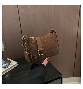 Detail of brown faux crocodile leather underarm bag with gold metal and resin chain strap