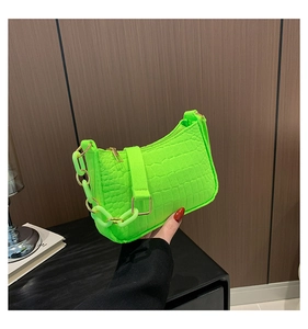 Detail of neon green crocodile pattern shoulder bag with chunky chain and gold hardware
