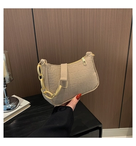 Detail of beige crocodile embossed handbag with yellow marble chain and gold zipper