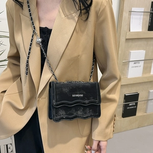 Sac bandoulière noir chic à bordure ondulée avec chaîne argentée sur mannequin
