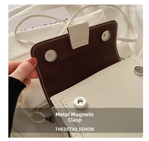 Dettaglio della chiusura magnetica su borsa a tracolla bianco crema con fodera marrone