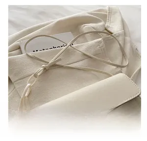 Dettaglio della borsa a tracolla crema con cinturino in pelle e catena in resina bianca