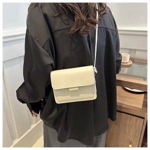 Vista dettagliata di una modella con una borsa a tracolla minimalista in pelle beige