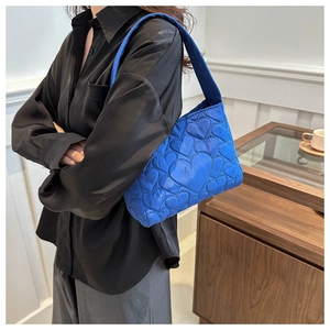 Détail du sac bandoulière matelassé bleu roi avec coutures en forme de cœur et texture