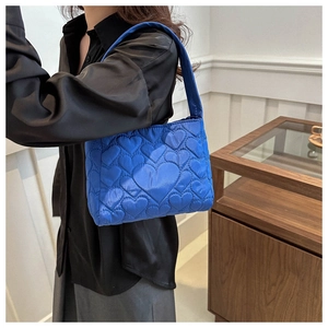 Détail du motif matelassé en cœur sur le sac à bandoulière bleu vif en mode lifestyle