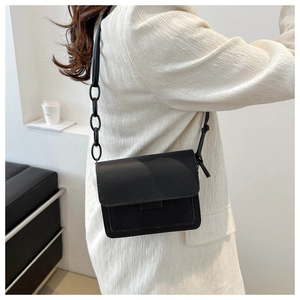 Dettaglio borsa a tracolla nera minimalista in pelle opaca con maglia della catena