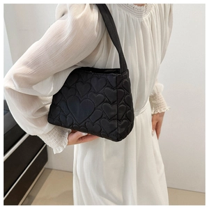 Détail du sac à bandoulière noir matelassé avec motif cœur et large bandoulière