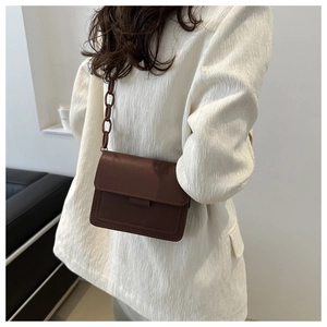 Dettaglio borsa a tracolla in pelle marrone con catena in resina e cuciture decorative