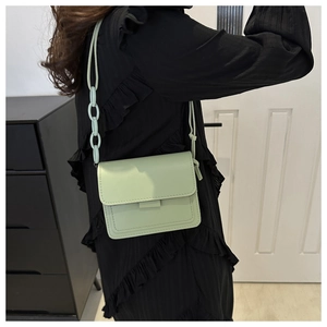 Borsa a tracolla verde menta minimalista con catena decorativa indossata su abito nero