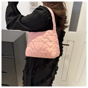 Détail d'un sac à bandoulière rose matelassé avec des motifs en forme de cœur