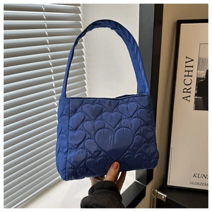 Détail d'un sac cabas bleu matelassé avec motifs de cœurs et bandoulière large