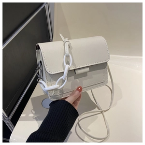 Dettaglio della borsa a tracolla crema minimalista con finitura opaca e manico a catena