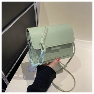 Dettaglio di una borsa a tracolla verde menta con catena decorativa e cuciture rifinite