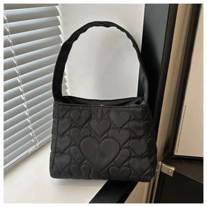 Détail du sac à main en nylon noir avec matelassage en cœur et texture du tissu