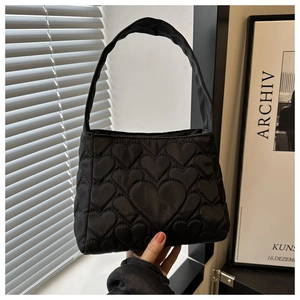 Détail d'un sac à main noir matelassé avec motifs de cœurs embossés et une poignée chic
