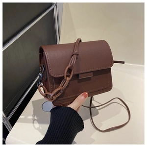 Dettaglio di una piccola borsa a tracolla marrone scuro in pelle opaca con catena
