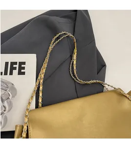 Close-up of golden leather shoulder bag featuring silver metal chain strap and PU texture