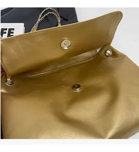 Detail of metallic gold chain bag with magnetic clasp and pleated faux leather texture