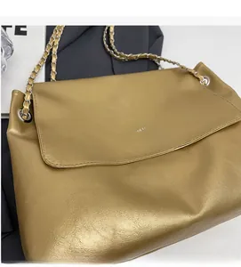 Detail of gold wrinkled leather shoulder bag featuring a metal chain strap and flap closure