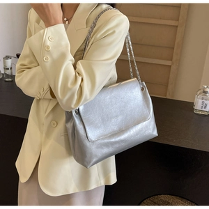 Close-up of metallic silver shoulder bag with flap closure and elegant chain strap detail