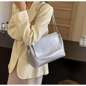 Detail of silver metallic crossbody bag with chain strap and shiny pleated texture