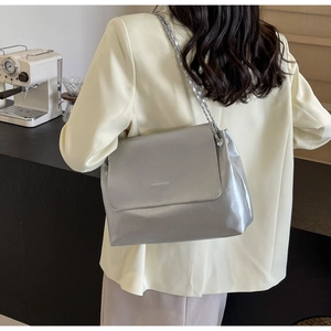 Detail of silver metallic shoulder bag with chain strap styled with a cream blazer